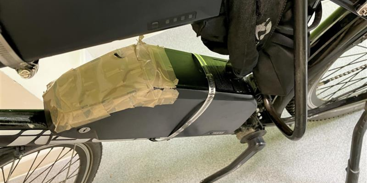 An e-bike with a dangerous condition battery held together by tape.