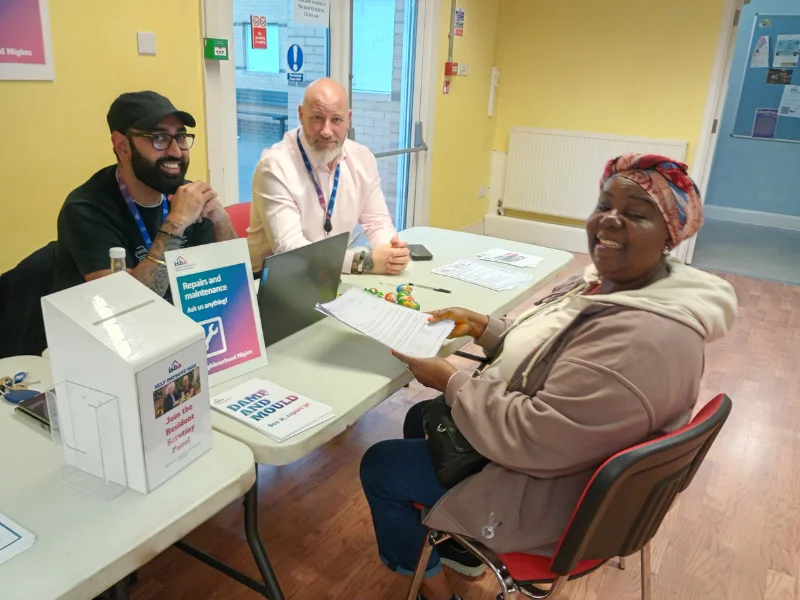 A resident is sitting at a table across from members of our repairs team giving her feedback.