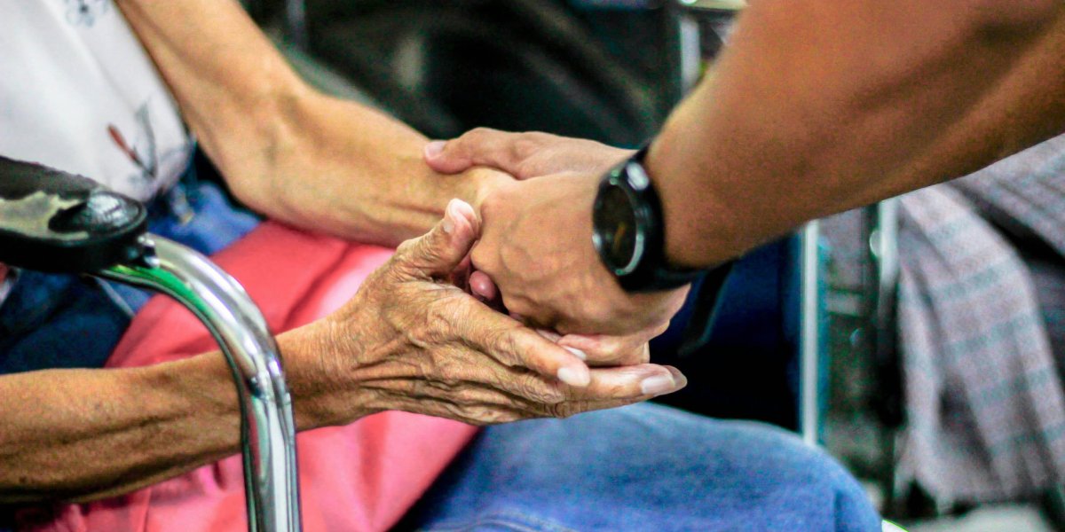 A man assisting an elderly woman.