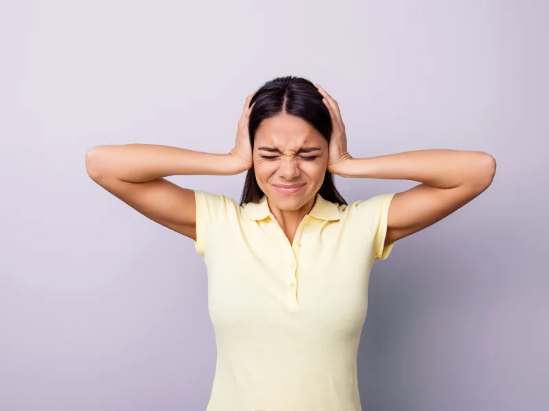 A woman covers her ears with her hands.