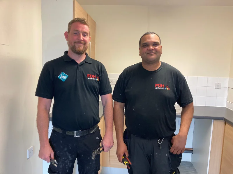 Two contractors smile as they work. 